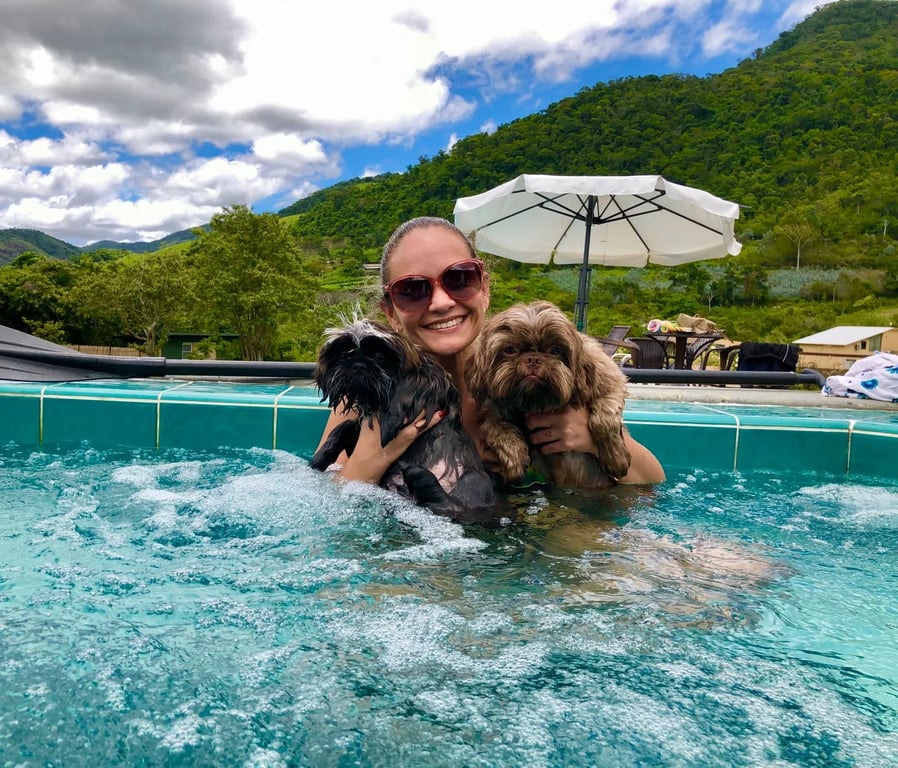 Hóspede com dois cachorros no ofurô da piscina, com a montanha ao fundo