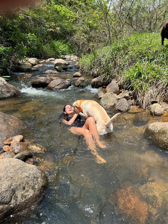 Hóspede e cachorro se banhando no rio da propriedade
