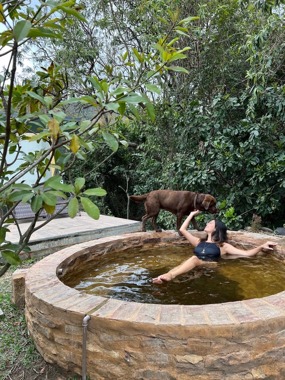 Hóspede e cachorro no hot tub ao lado da mata